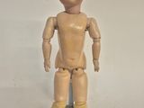 a small wooden doll that is standing on a rock