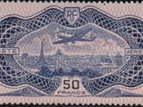 a close up of a stamp with a picture of a plane flying over a city