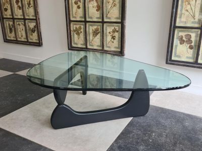 a glass table with a black base on a checkered floor