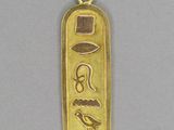 un gros plan d'un pendentif plaqué or orné d'un hiéroglyphe égyptien