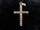 un gros plan d'une croix en argent sur fond noir