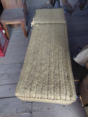 a wicker bench sitting on the porch of a house