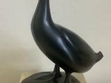 statue of a black duck on a marble base on a table