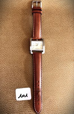 an image of a watch sitting on top of a brown leather bag