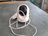 a white camera sitting on top of a table next to a book shelf