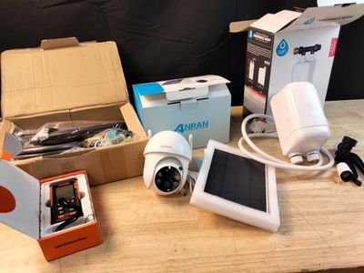 a box with a solar panel, a camera, a cell phone, and a solar panel on a table