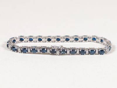un gros plan sur un bracelet « tennis » orné de pierres bleues