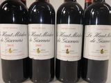 four bottles of red wine are lined up on a table