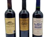 three bottles of wine are lined up on a white surface