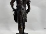 bronze statue of a man holding a bag on a black base
