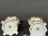 two white porcelain dishes with colorful flowers on them sitting on a table