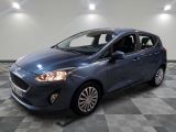 une Ford Fiesta bleue garée dans une pièce au sol carrelé