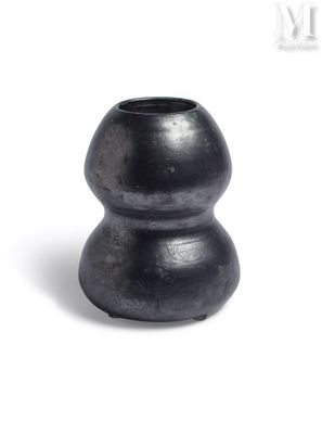 un vase noir posé sur une surface blanche