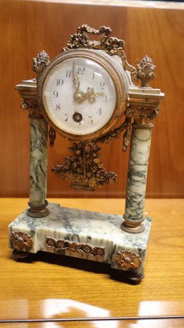 Petite pendule portique marbre cadran émaillé blanc, décor aux nœ...