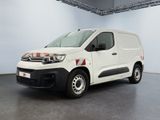 La camionnette blanche est garée dans une pièce au sol gris.