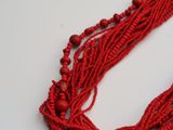 some red beads are on a white surface and some are on a table