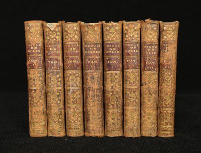 five old books are lined up on a black surface