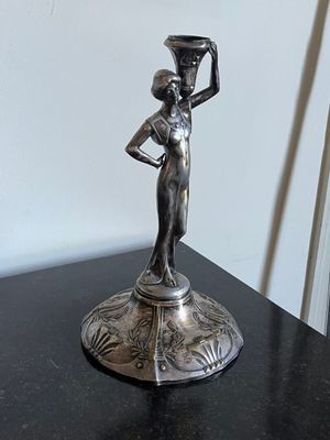 une statue représentant une femme tenant un pot posé sur une table