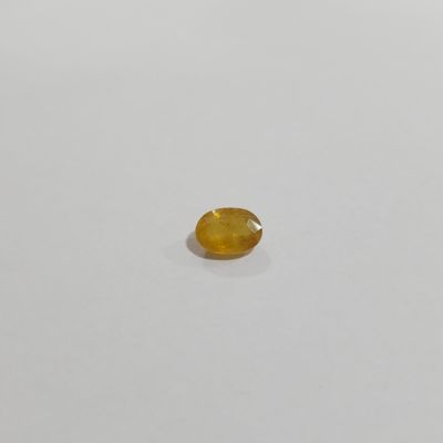 a yellow sapphire stone on a white surface