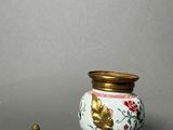 a small vase with a lid sitting next to a smaller one