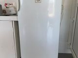 a small white refrigerator in a kitchen with tile flooring