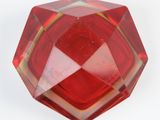 a close up of a red glass object on a white surface