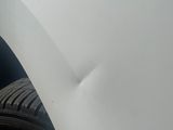 the front bumper of a white car with a flat tire