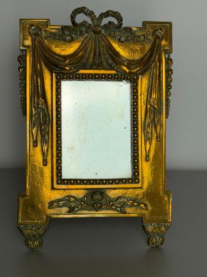 an ornate gold frame with a mirror on top of a table