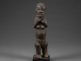 une statue en bois représentant un homme qui porte ses mains à son visage