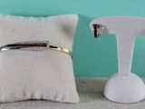 pair of gold and silver cuff earrings and a white pillow on a blue background