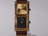 a gold watch with a black face on a stand