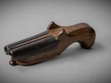 un gros plan d'un pistolet posé sur une table, sur fond gris