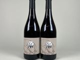 two bottles of red wine sitting on top of a table