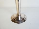 une bougie argentée posée sur une table blanche