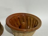 two brown bowls sitting next to each other on a white surface