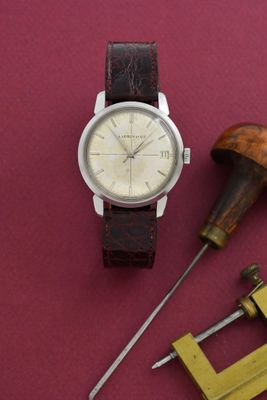 une montre posée sur une table, à côté de deux outils