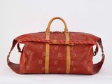 a red duffel bag with brown handles on a white background