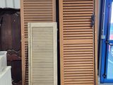 deux volets en bois dans une pièce, avec un tableau accroché au mur derrière eux