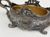 a silver bowl with a handle on a white surface