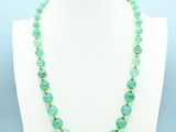 a green beaded necklace on a white mannequin