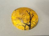 a yellow stone with a tree on it sitting on a table