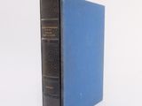 an old blue book sitting on top of a white surface