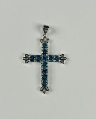 une croix en argent ornée de cristaux bleus sur fond blanc
