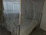 un lit muni d'une moustiquaire, dans une chambre