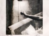 black and white photograph of a hand holding a lamp above a bathtub
