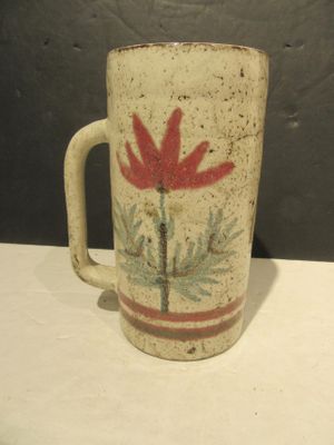 a coffee mug with a red flower on it on a table