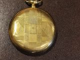 a gold pocket watch on a brown leather surface