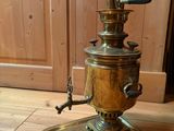 a brass coffee grinder sitting on a wooden floor