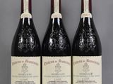 three bottles of red wine are lined up on a table