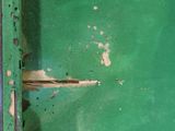 a close up of a green metal door with a rusted handle